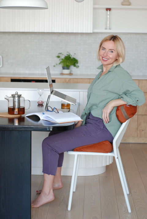 Smiling beautiful blond woman at a home office sitting on a natural seat pillow filled with organic buckwheat husk 