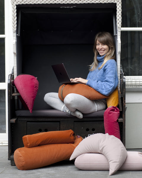 smiling woman working at the computer among buckwheat cushions in different colours