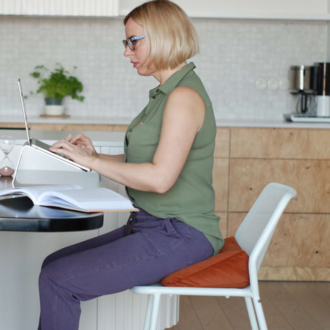 woman working remotely sitting in a chair with an orange wedge pillow
