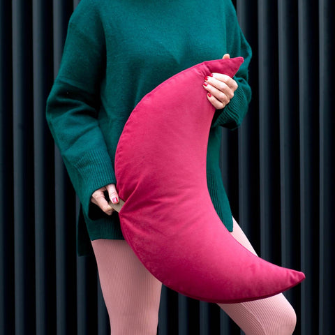 person holding a pink cushion in the shape of half a moon