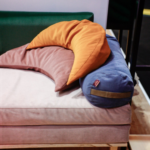 blue yoga bolster and pink moon cushions lying on the sofa