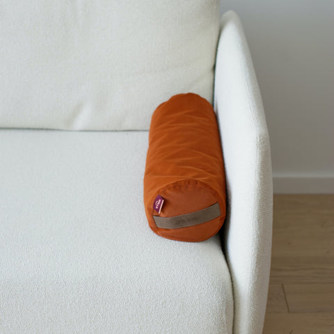a small buckwheat roll in Colorado orange lying on a bright sofa